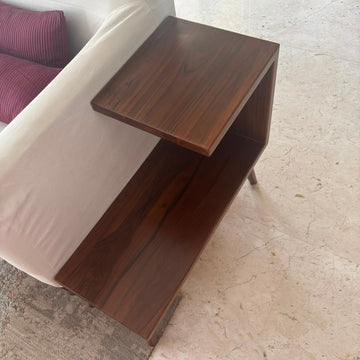 Wooden side table next to a bed with purple bedding